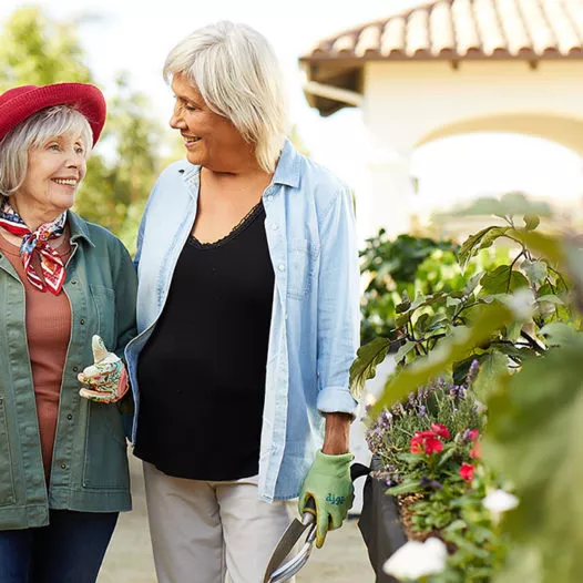 Two senior ladies are smiling in the garden