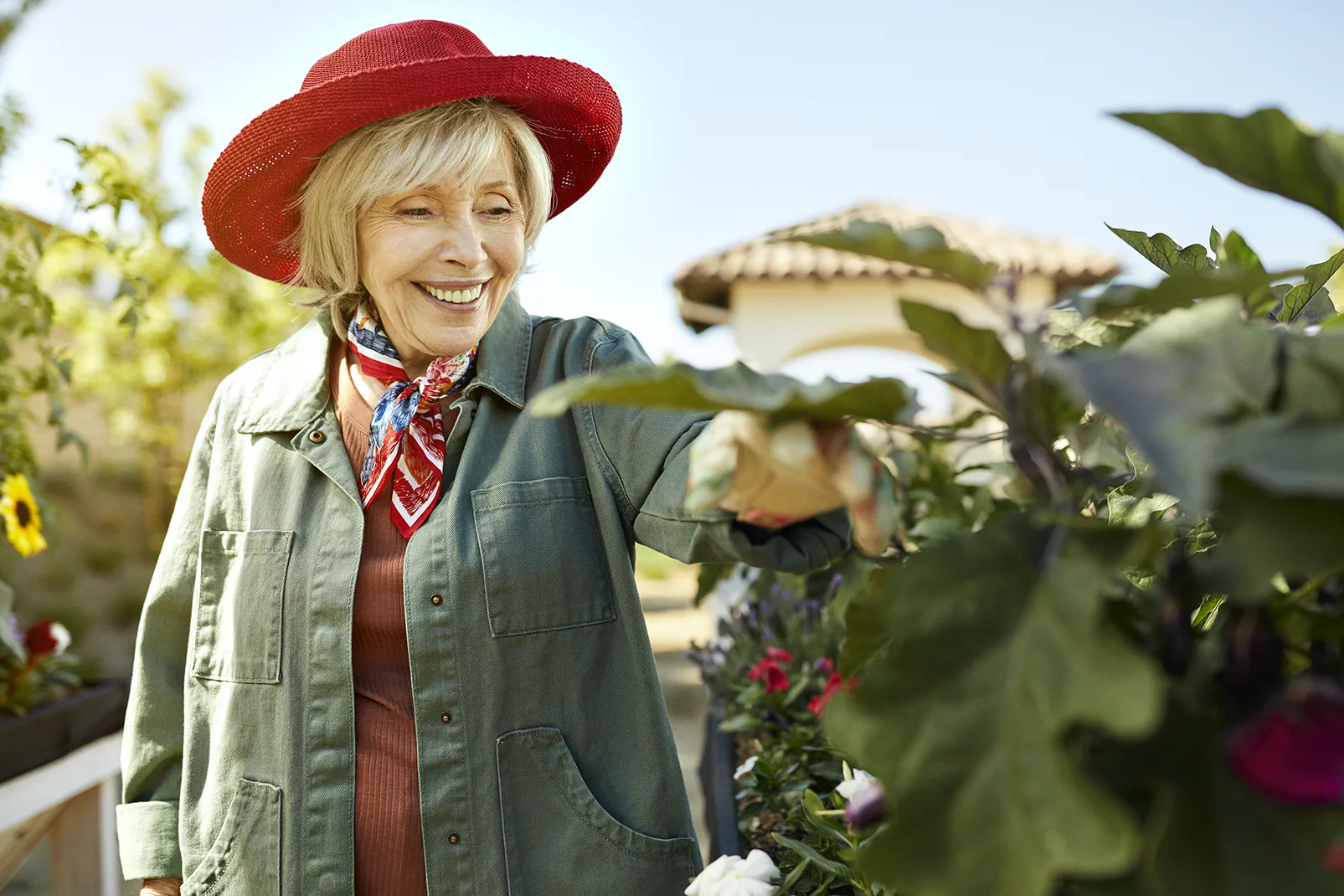 Senior lady in a red hat smiling in the garden