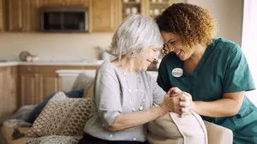 Caregiver is holding senior lady's hand