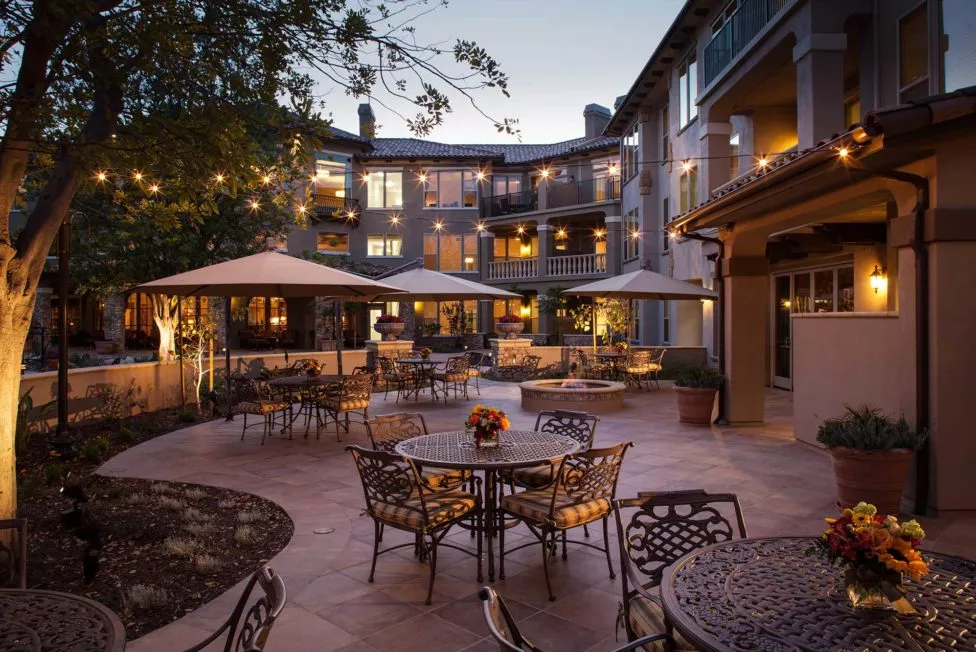 Capriana outdoor patio by night with table, chairs and string lights