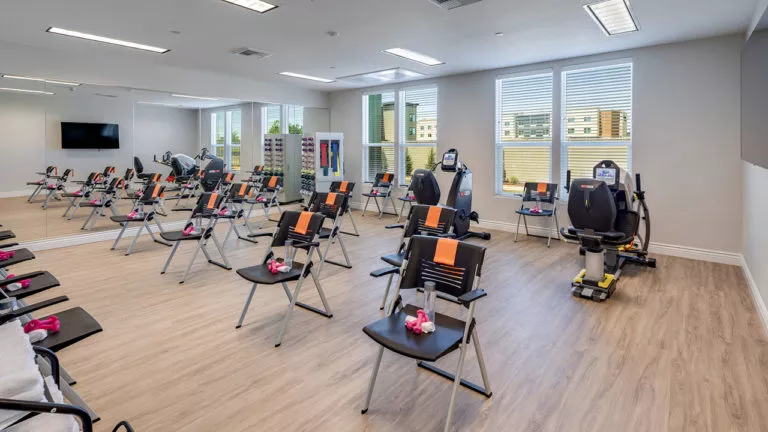 The exercise room filled with chairs and set up for a class