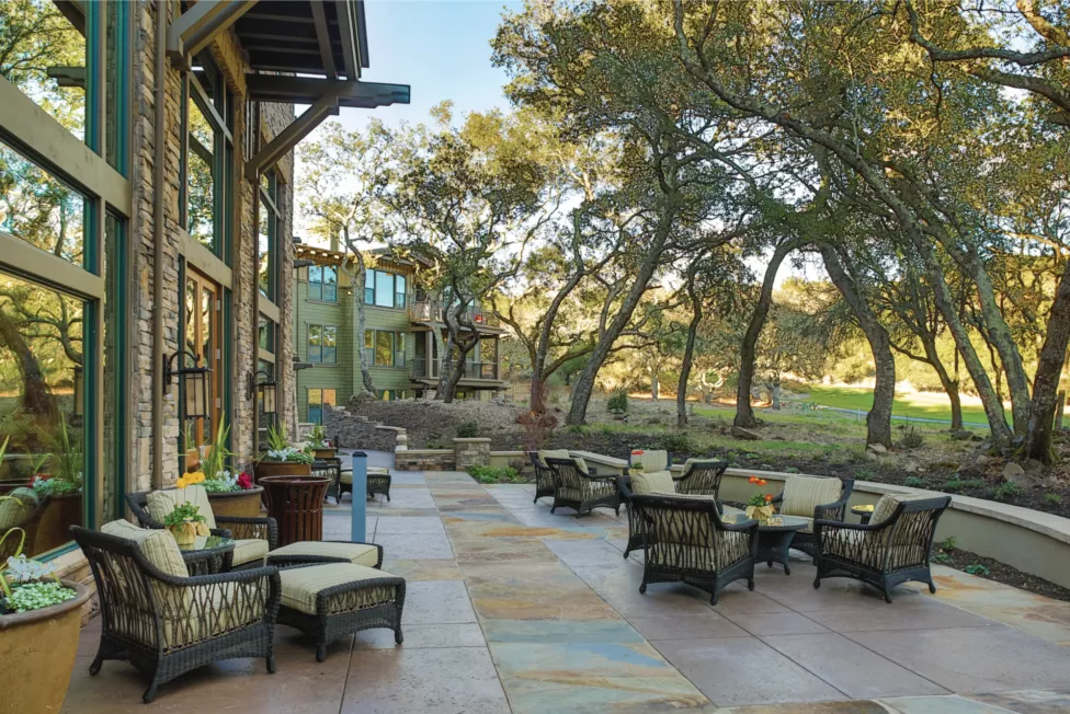 Fountaingrove patio with comfortable chairs and tables, surrounded by trees and a garden