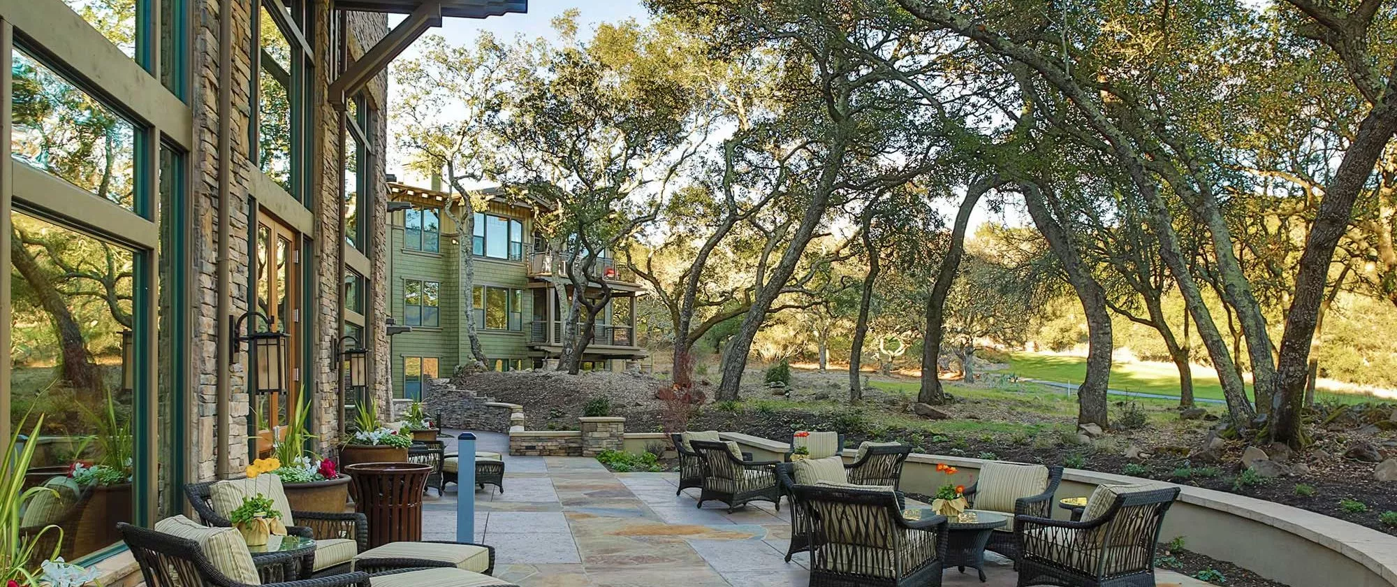 Fountaingrove patio with comfortable chairs and tables, surrounded by trees and a garden