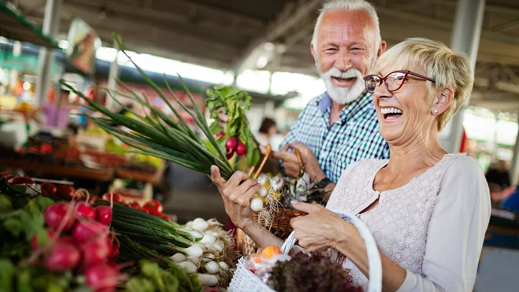 Senior couple is picking vegetables and laughing