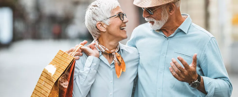 Older couple with shopping bags laughing at each other