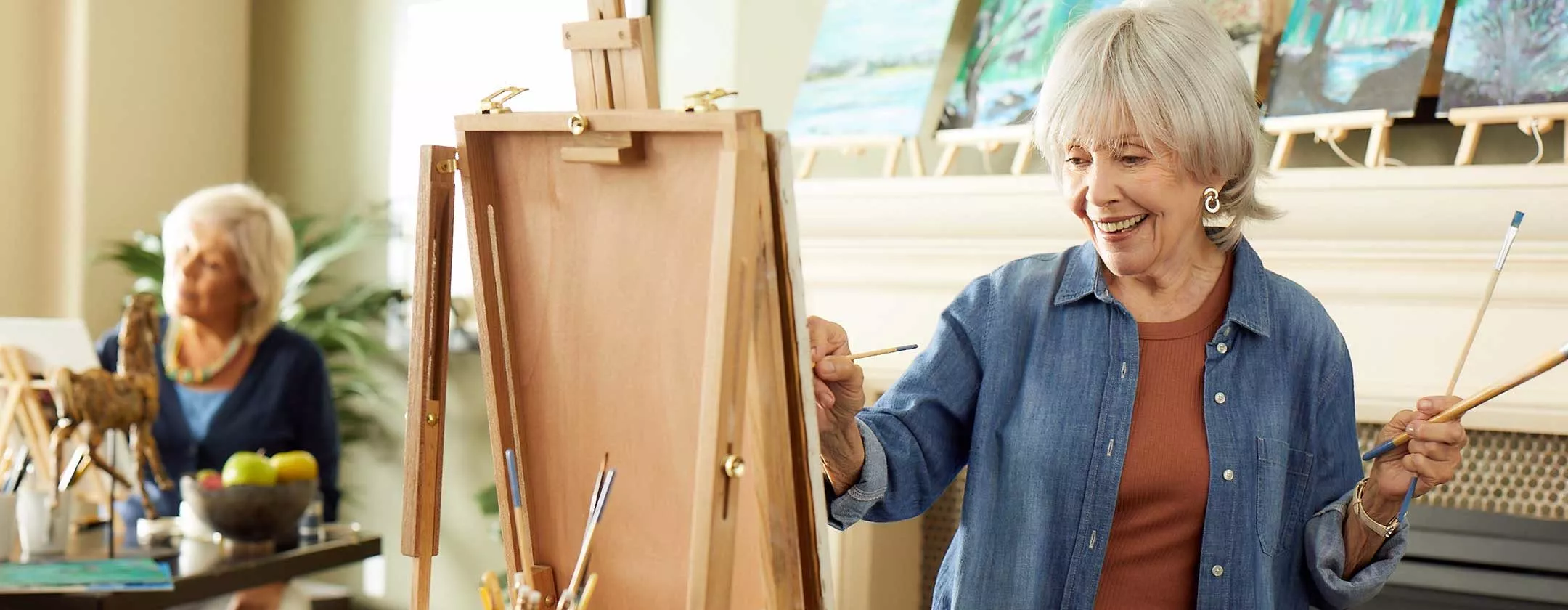 Senior lady painting on easel in art studio