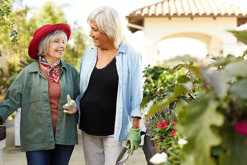 Two senior ladies are smiling in the garden