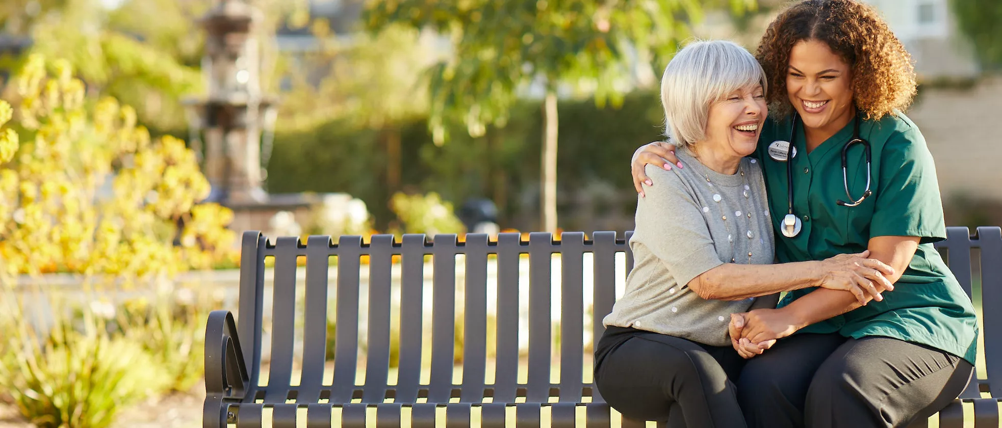 Care giver and senior lady are sitting on a bench