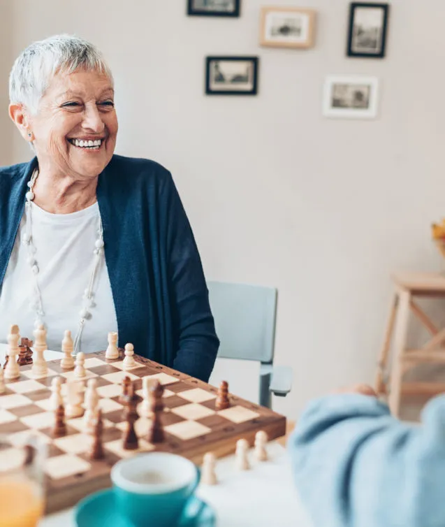 Happy senior couple playing chess at home