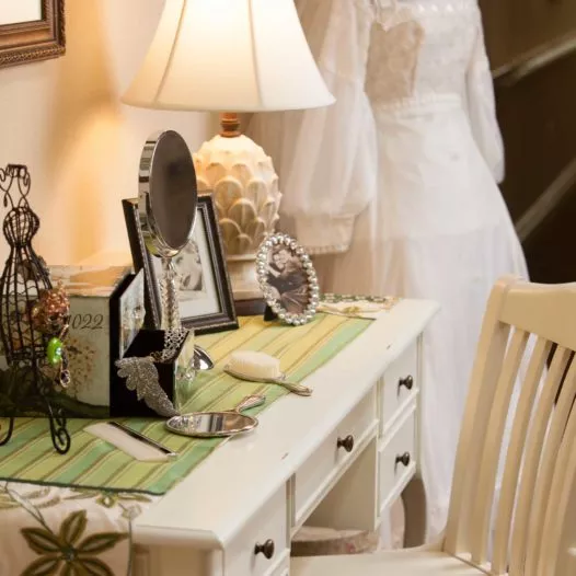 Beautiful white wooden table with photos and old wedding dress