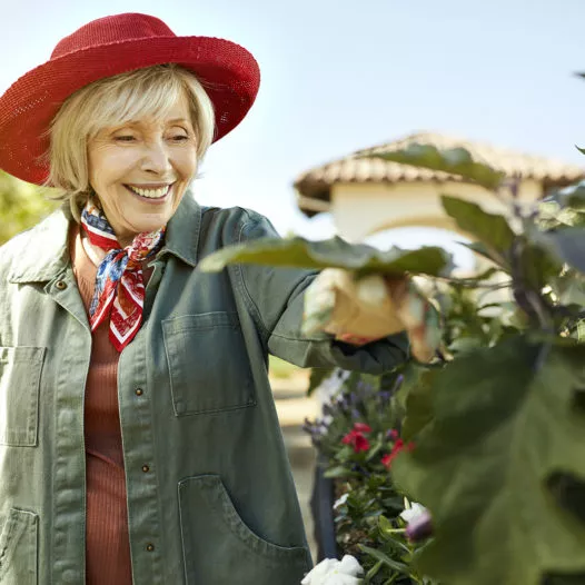 Senior lady in a red hat smiling in the garden