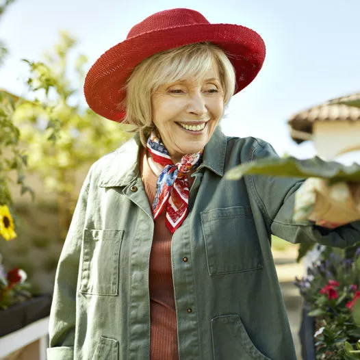 Senior lady in a red hat smiling in the garden