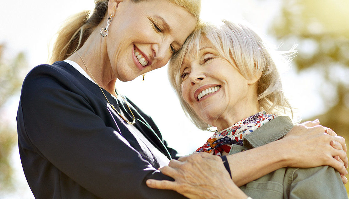 Caregiver is giving a hug to a senior lady