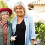 Two senior ladies are smiling in the garden